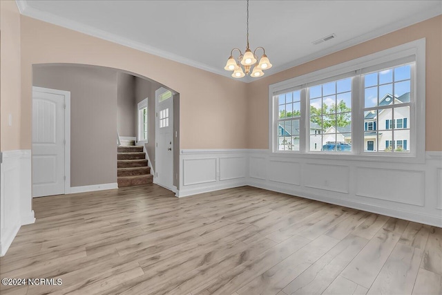 unfurnished room featuring a chandelier, crown molding, and light wood-type flooring