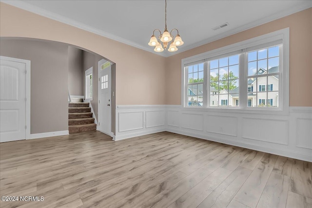 empty room with light hardwood / wood-style floors, ornamental molding, and an inviting chandelier