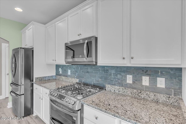 kitchen with white cabinetry, decorative backsplash, light stone countertops, appliances with stainless steel finishes, and light hardwood / wood-style flooring