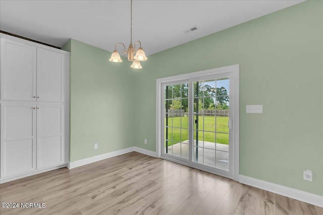 unfurnished dining area featuring light wood-type flooring and a chandelier