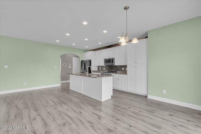 kitchen featuring white cabinets, light hardwood / wood-style flooring, appliances with stainless steel finishes, and a center island with sink