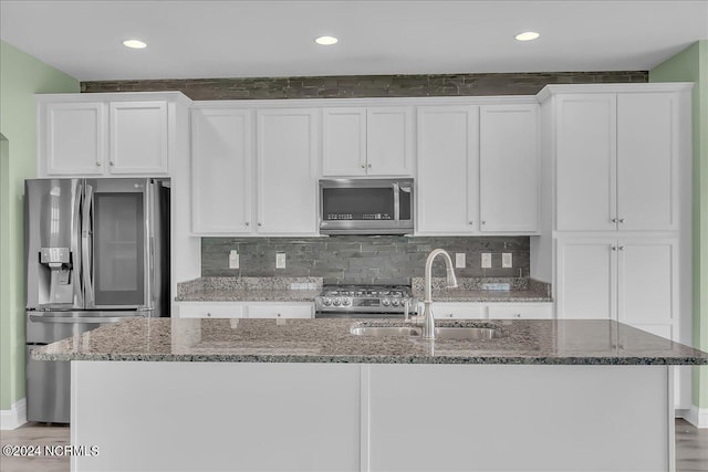 kitchen featuring stainless steel appliances, white cabinets, an island with sink, sink, and light hardwood / wood-style floors