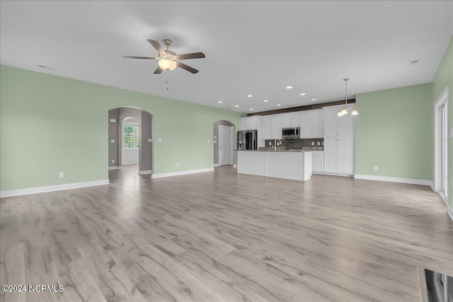 unfurnished living room with ceiling fan with notable chandelier, light hardwood / wood-style flooring, and sink