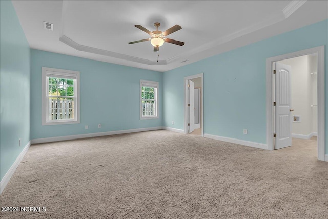 carpeted empty room with ceiling fan and a raised ceiling