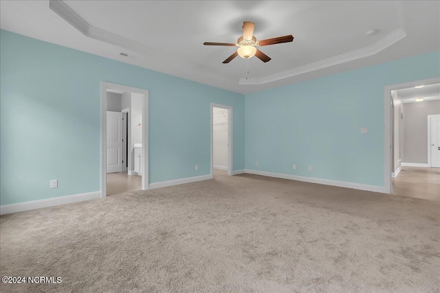 spare room with a raised ceiling, crown molding, carpet floors, and ceiling fan