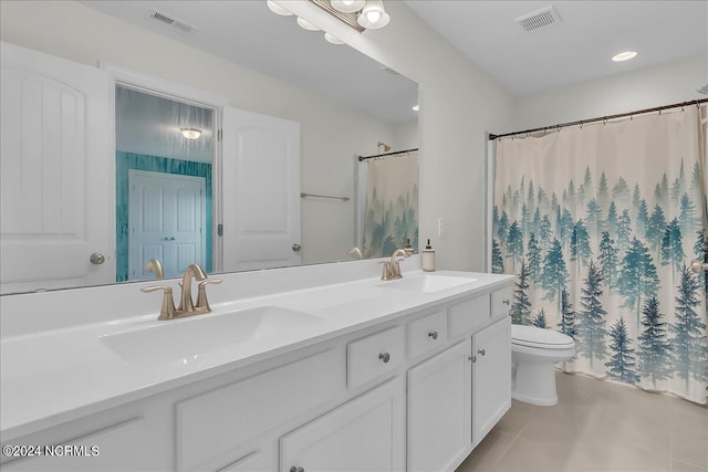 bathroom featuring toilet, tile patterned floors, and dual bowl vanity