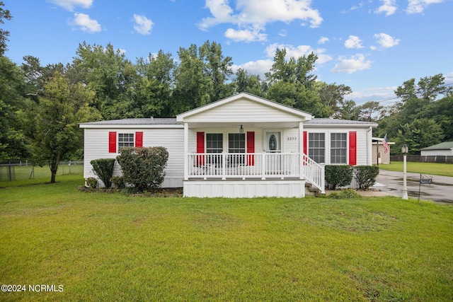 manufactured / mobile home with covered porch, metal roof, a front lawn, and fence