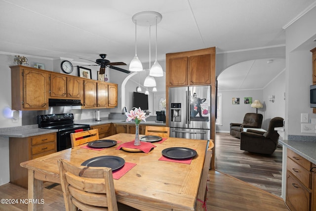 kitchen with arched walkways, under cabinet range hood, brown cabinets, black electric range oven, and stainless steel fridge