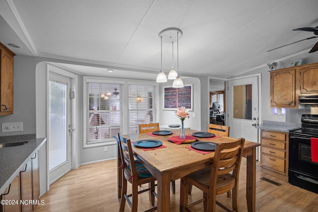 dining room featuring a textured ceiling, lofted ceiling, light wood-style flooring, visible vents, and a ceiling fan