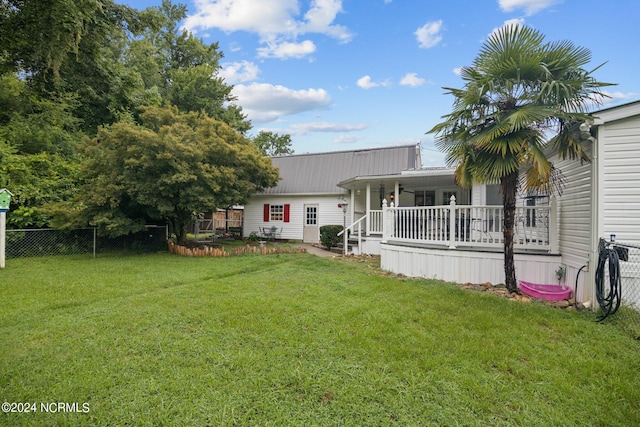 exterior space featuring covered porch, metal roof, a lawn, and fence