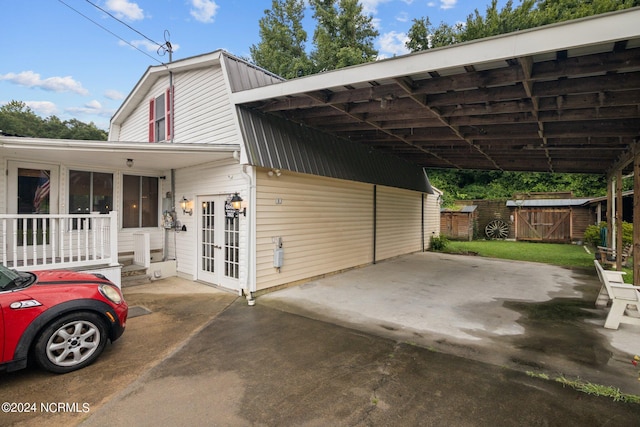 exterior space with a storage shed, metal roof, fence, french doors, and a carport