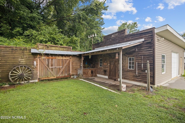 back of property with a garage, a yard, and an outdoor structure