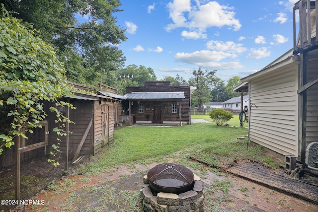 view of yard with an outdoor fire pit, an outdoor structure, and fence