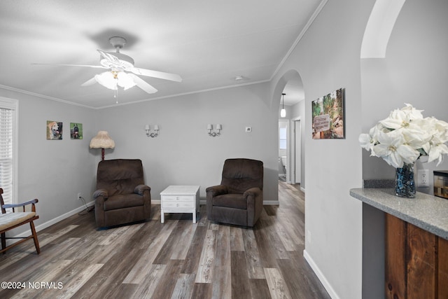 living area with arched walkways, baseboards, wood finished floors, and crown molding