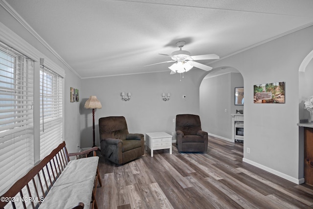 sitting room featuring baseboards, ornamental molding, arched walkways, and wood finished floors