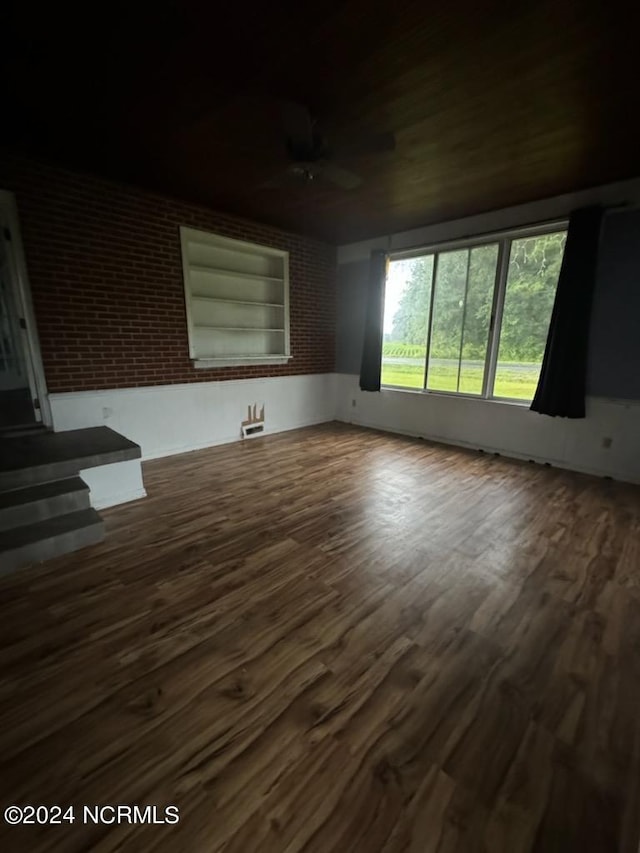 empty room with ceiling fan, brick wall, and wood-type flooring