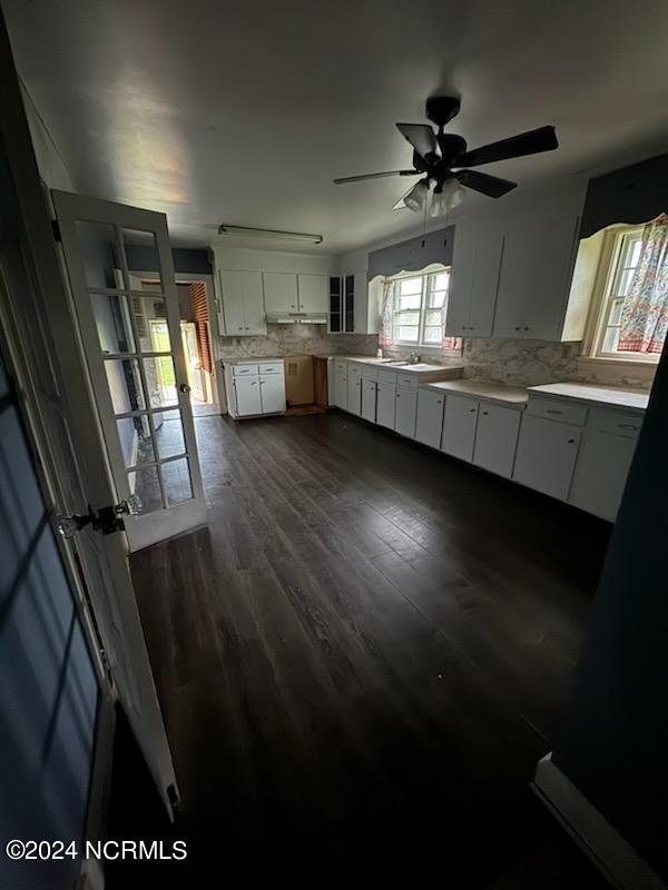 kitchen featuring tasteful backsplash, ceiling fan, dark wood-type flooring, sink, and white cabinets