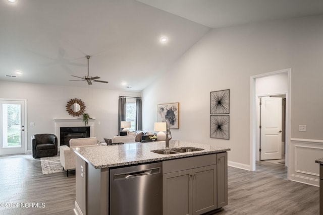 kitchen featuring light wood finished floors, dishwasher, gray cabinets, a sink, and a glass covered fireplace