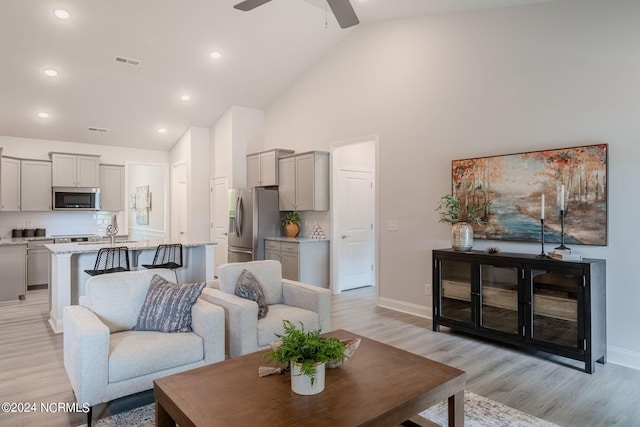 living room featuring ceiling fan, light hardwood / wood-style flooring, and high vaulted ceiling