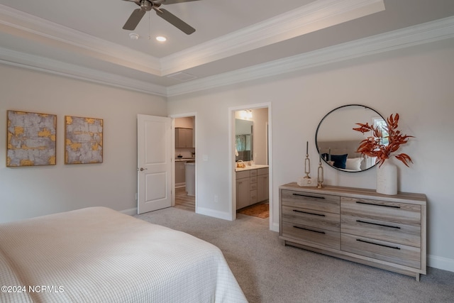 carpeted bedroom featuring a raised ceiling, ornamental molding, ensuite bathroom, and ceiling fan