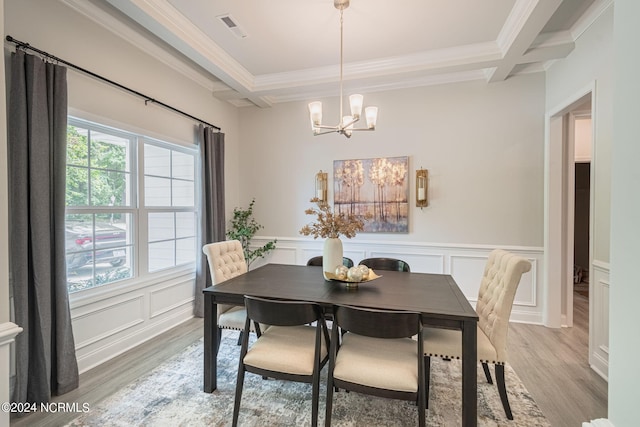 dining space featuring ornamental molding, coffered ceiling, and light hardwood / wood-style flooring