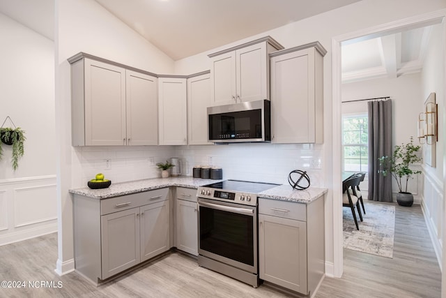 kitchen with appliances with stainless steel finishes, gray cabinets, tasteful backsplash, and light hardwood / wood-style flooring