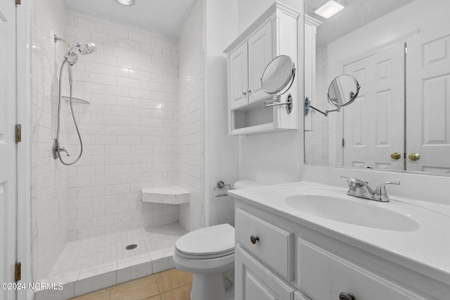 bathroom featuring a tile shower, tile patterned flooring, vanity, and toilet