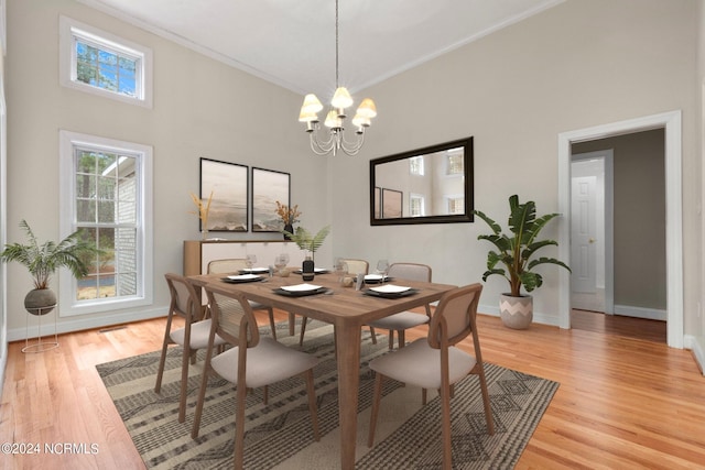 dining space featuring ornamental molding, light hardwood / wood-style floors, a high ceiling, and an inviting chandelier