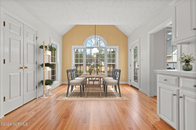 dining space featuring a textured ceiling, light hardwood / wood-style flooring, and lofted ceiling