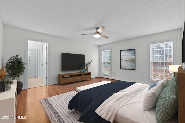 bedroom with multiple windows, ceiling fan, a textured ceiling, and light wood-type flooring