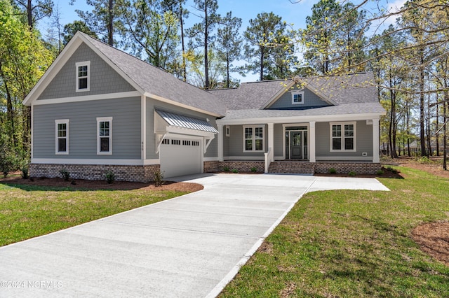 craftsman-style home with a garage, driveway, a front yard, and a shingled roof