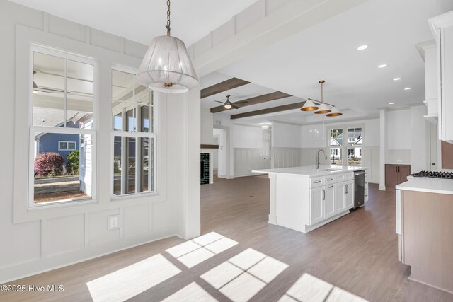 kitchen with crown molding, built in microwave, stainless steel range with gas stovetop, an island with sink, and a sink