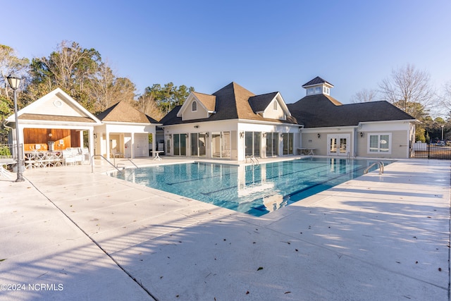 pool with a patio area, french doors, and fence