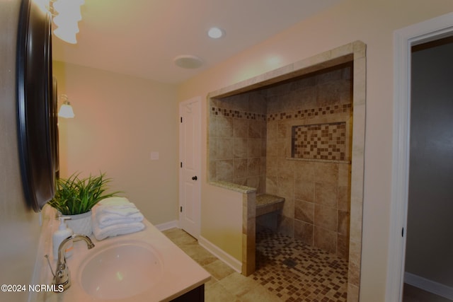 bathroom with tile patterned flooring, vanity, and a tile shower