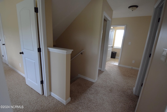 corridor with carpet, baseboards, and an upstairs landing