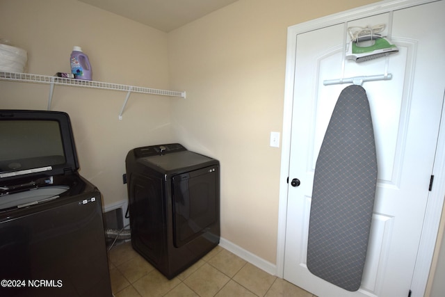 laundry room with laundry area, baseboards, washing machine and clothes dryer, and light tile patterned floors