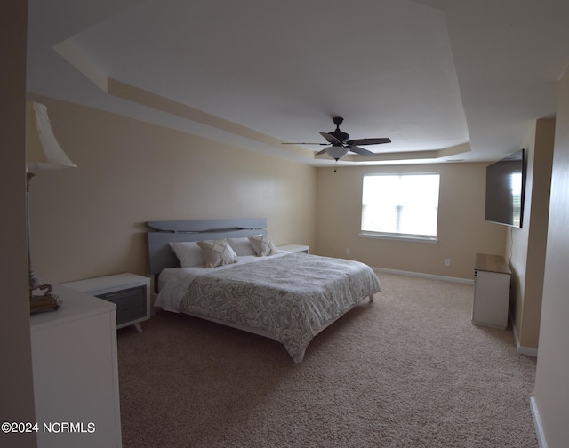 carpeted bedroom featuring ceiling fan and a tray ceiling