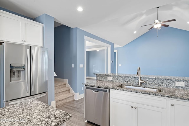 kitchen featuring white cabinetry, stainless steel appliances, and dark stone countertops