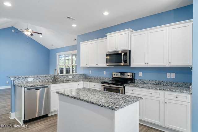 kitchen featuring ceiling fan, appliances with stainless steel finishes, white cabinetry, and a kitchen island