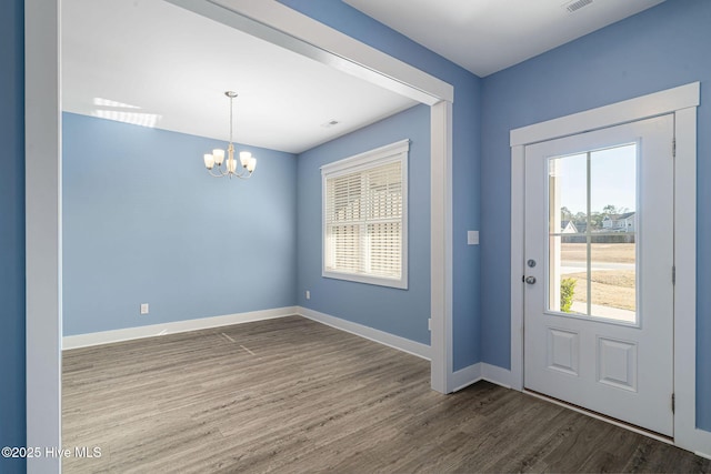 entryway with an inviting chandelier, a wealth of natural light, and dark hardwood / wood-style floors