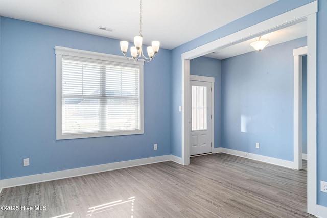 spare room featuring a chandelier and hardwood / wood-style flooring