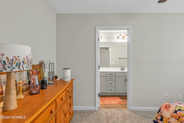 carpeted bedroom with ensuite bathroom, sink, and ceiling fan