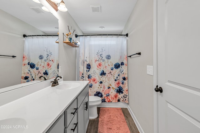 bathroom with toilet, hardwood / wood-style floors, walk in shower, and vanity