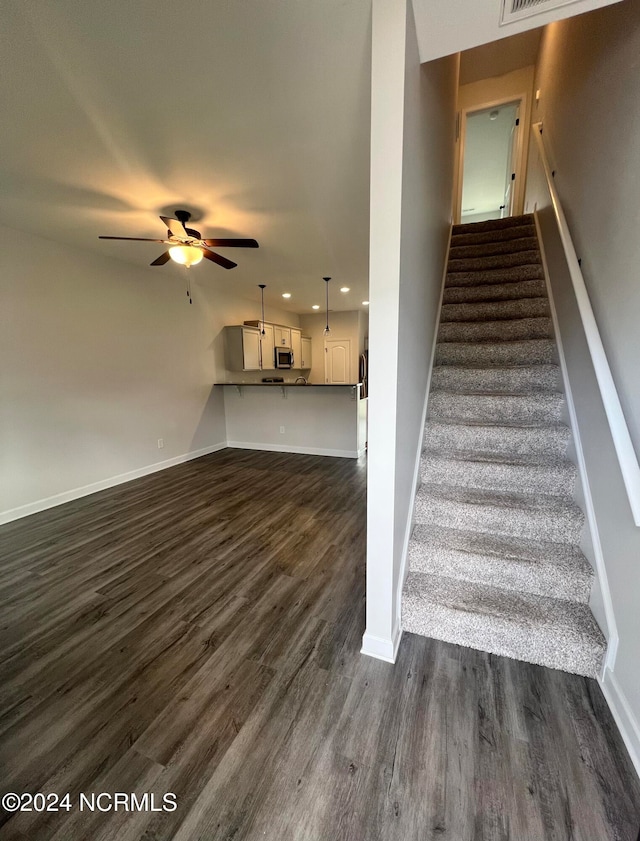 stairs featuring wood-type flooring and ceiling fan