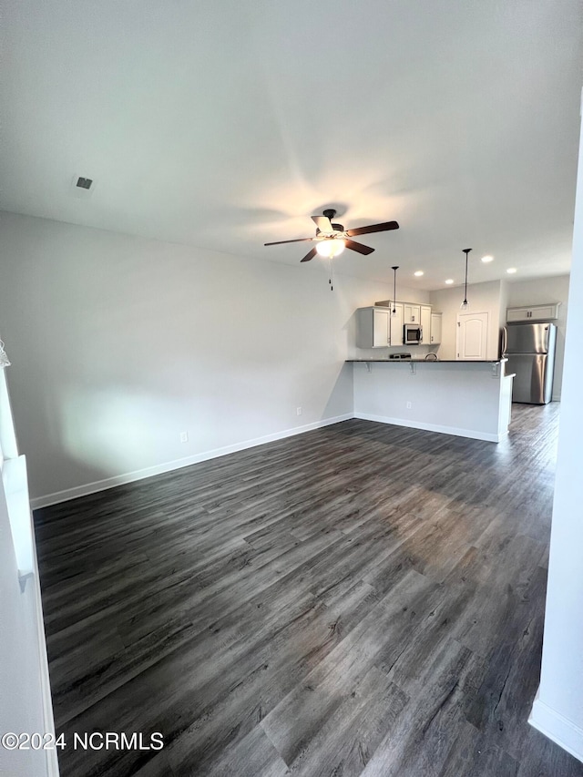 unfurnished living room featuring dark wood-type flooring and ceiling fan