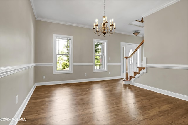 empty room with dark wood-type flooring, ornamental molding, and an inviting chandelier