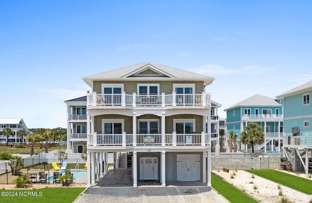 coastal inspired home featuring metal roof, gravel driveway, fence, and a balcony