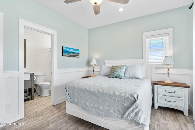 445 E Third St, Ocean Isle Beach, NC 28469 - bedroom featuring wood finished floors, ensuite bath, a wainscoted wall, a ceiling fan, and recessed lighting
