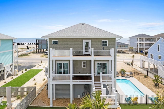 445 E Third St, Ocean Isle Beach, NC 28469 - rear view of house with a balcony, a fenced backyard, a shingled roof, and a water view