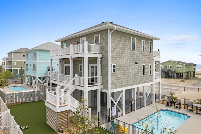 445 E Third St, Ocean Isle Beach, NC 28469 - back of house with a balcony, a fenced backyard, and a community pool